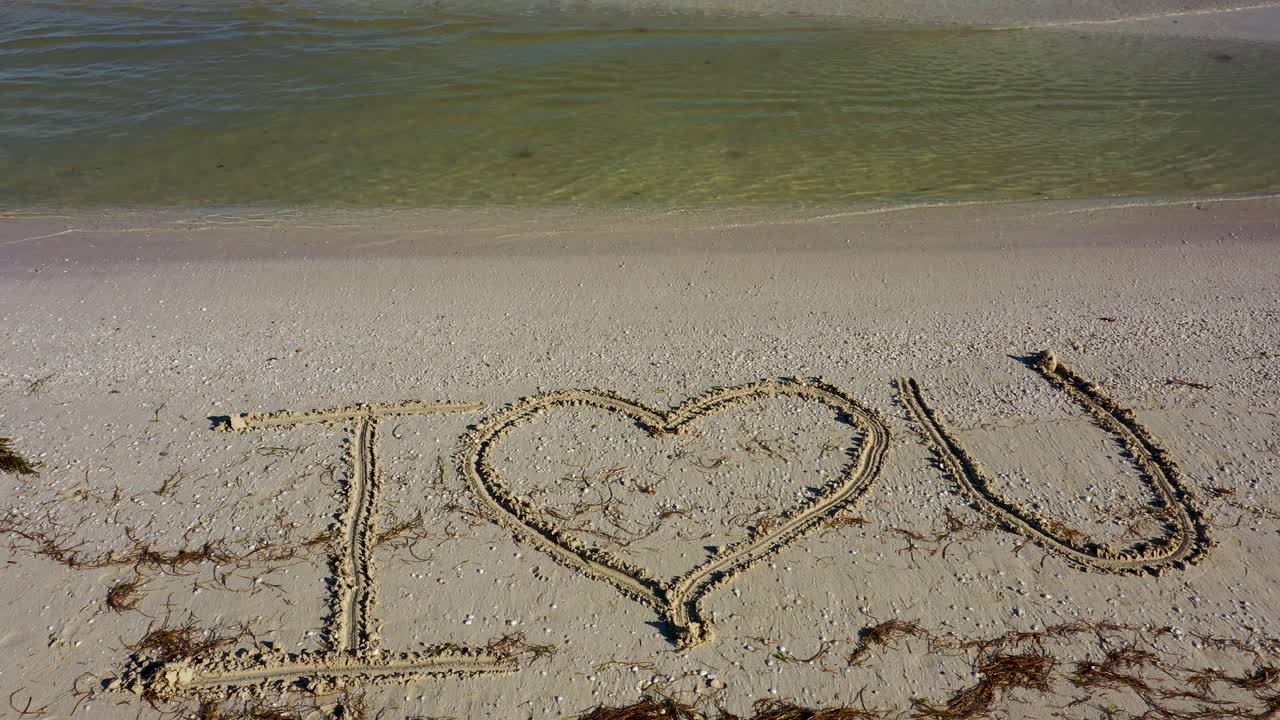 나는 물이 해변에 무릎을 꿇고 모래에 쓰여진 당신을 사랑합니다