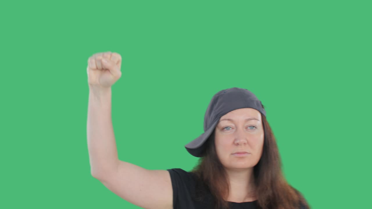 mujer manifestante con la mano levantada apretada en el puño en fondo verde. revolución social femenina. rebelión nacional y manifestación. feminismo ang concepto de poder de la niña.