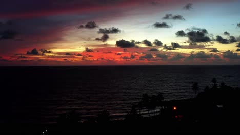 aerial drone rising shot of a stunning red sunrise with the vast ocean below on a warm summer morning in northern brazil near joao pessoa