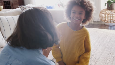 ein pre-teen-mädchen kniet vor ihrer mutter und gibt ihr ein hausgemachtes geschenk, über die schulter