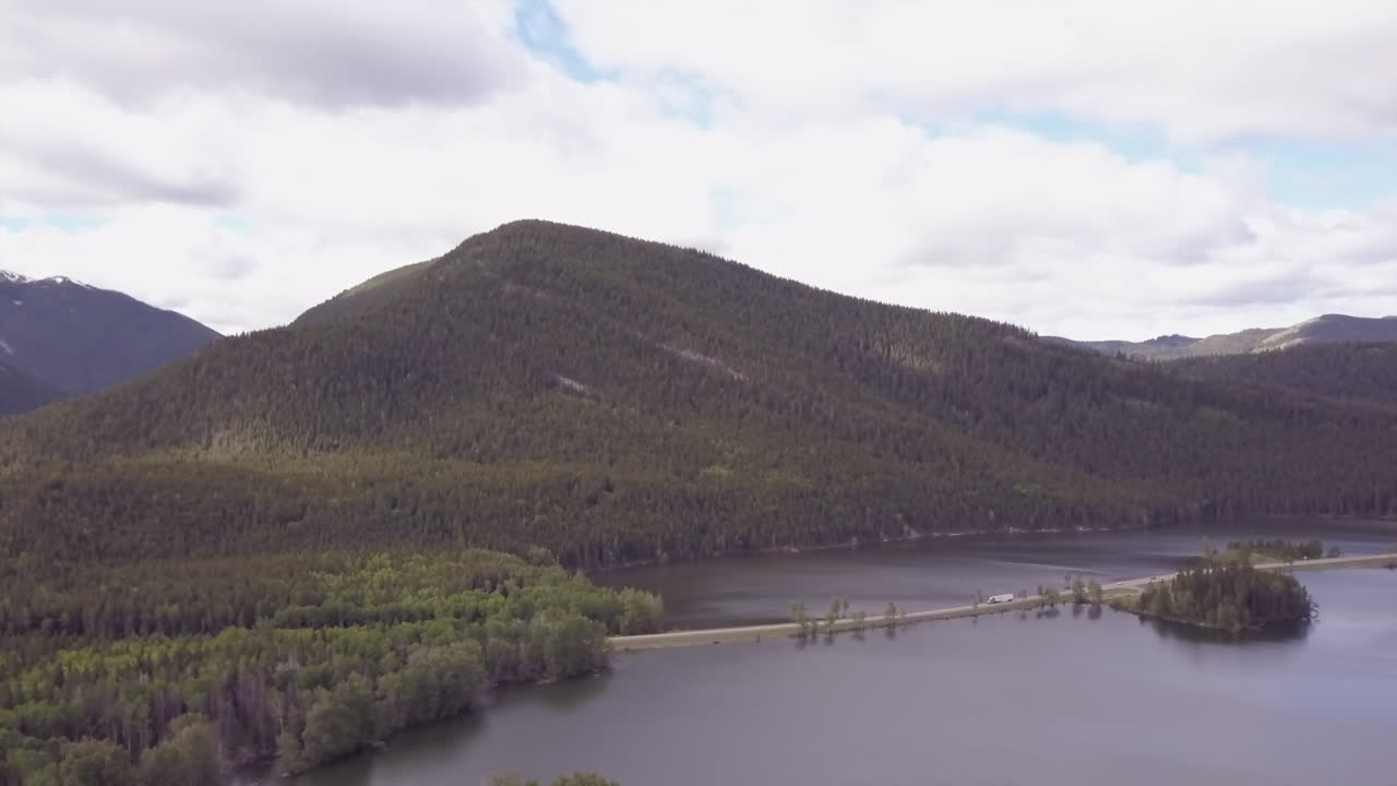 автомобильное движение по дороге, проложенной через небольшое голубое горное озеро