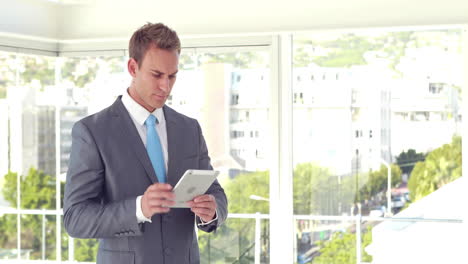 smiling businessman using his tablet and looking at camera