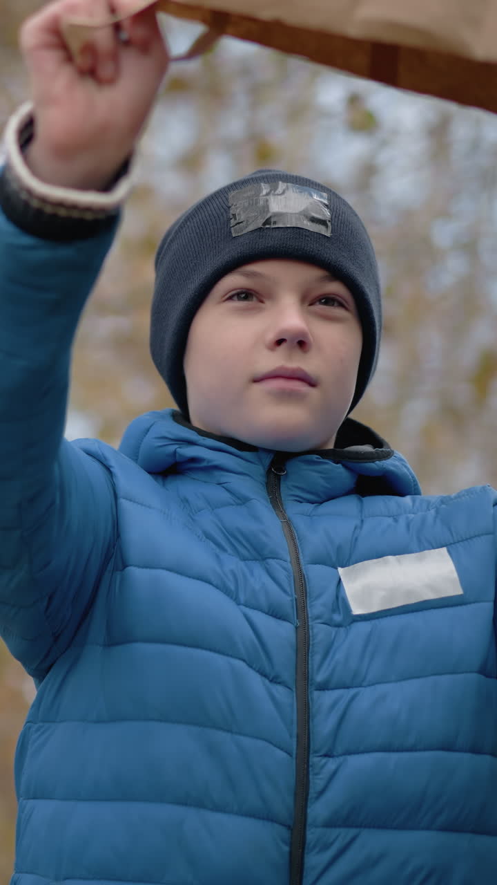 작은 소년은 마른 나무를 따라 사려 깊게 고, 그의 가방을 거꾸로 뒤집고 땅에 건조한 잎을 부어, 활기찬 가을 잎과 자연에 둘러싸여