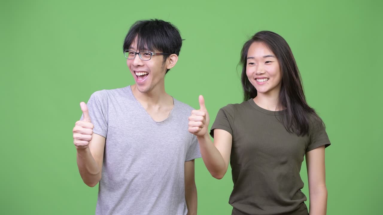 Young Asian couple giving thumbs up together