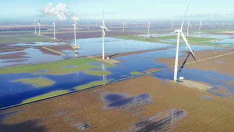 wind turbines operating in flooded fields with a power station running in the background