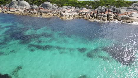 drone aerial 360 showing crystal clear blue tropical water in bay of fires tasmania slow motion 60fps