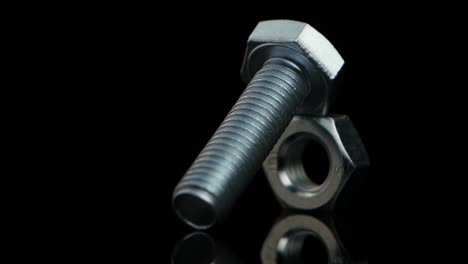 a close-up of a metal bolt and nut on a black background