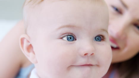 close up of mother playing on bed at home with baby son