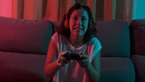 young woman playing a video game sitting on the couch and winning the game