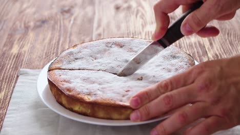 a man's hand cutting an apple pie with knife. close-up video