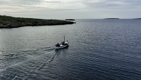 old sailing boat glides through the waters of sa nitja natural port in menorca spain