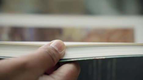 Close-up-of-hand-flicking-through-the-pages-of-a-book