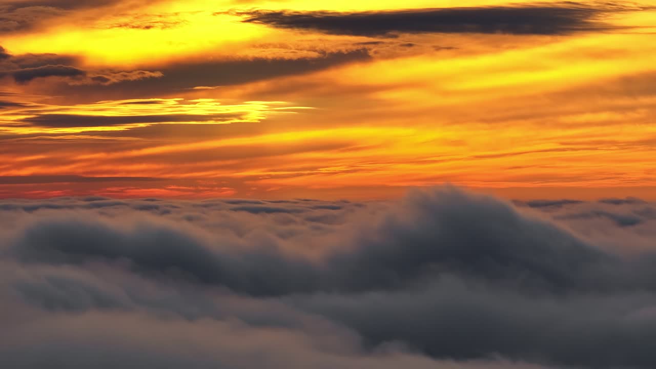 Dramatischer orangefarbener Sonnenuntergang über dicken, rollenden Wolken in großer Höhe aus der Luft aufgenommen