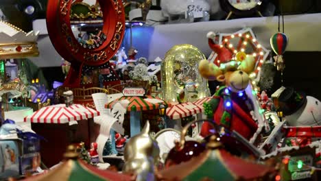 a person choosing with his hand christmas toys, snowball and carousel with multi-colored lights in a christmas market