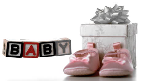 blocks spelling baby falling beside booties and gift box