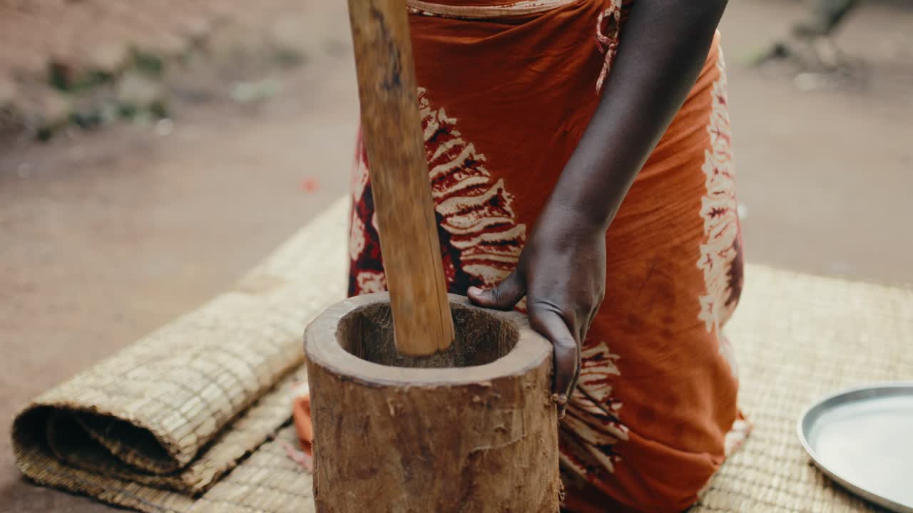 Black African manually grinding coffee beans with wooden mortar and pestle