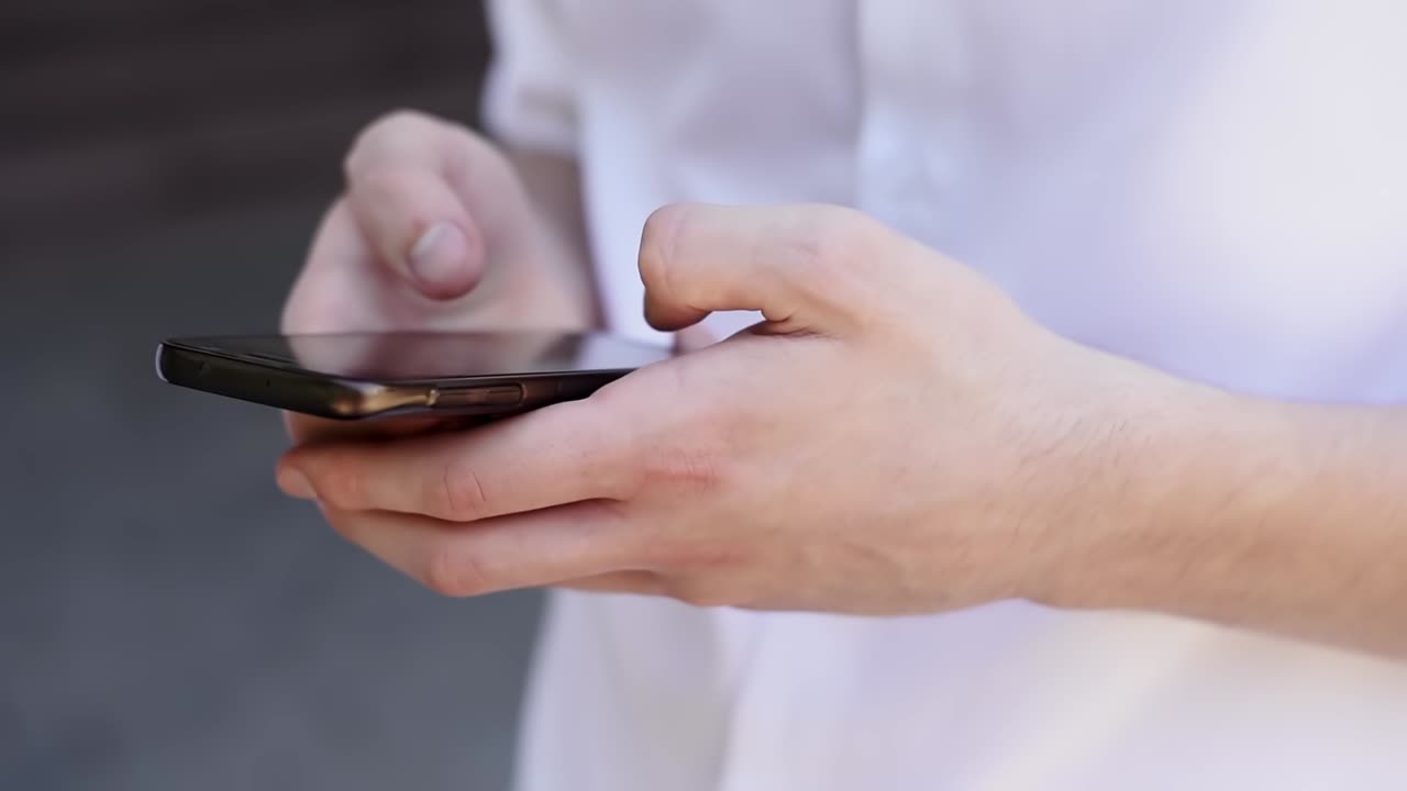 Caucasian man in white shirt writing messages on the phone. Close up