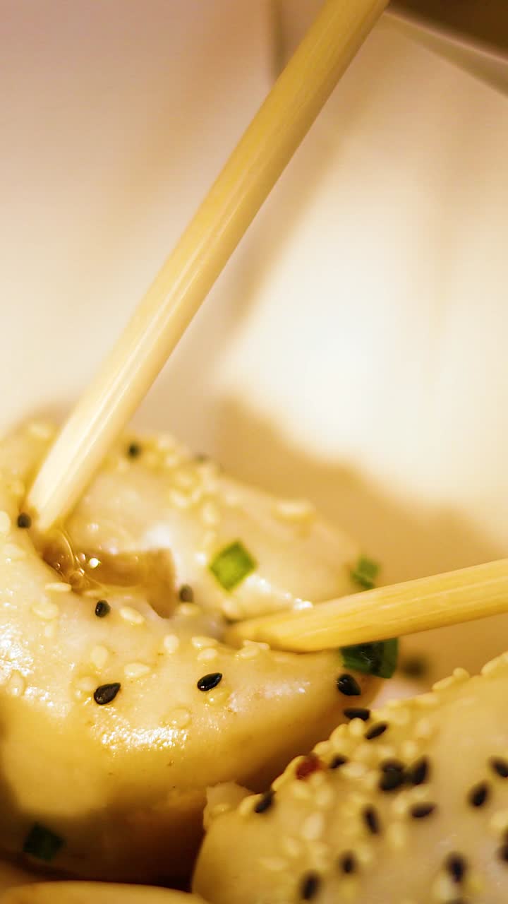 Chopsticks picking up pan-fried buns