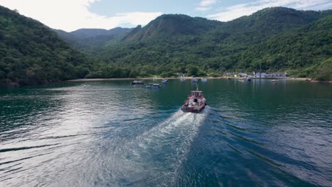 orbit shot of garbage boat sailing towards ilha grande island to pick up trash, brazil