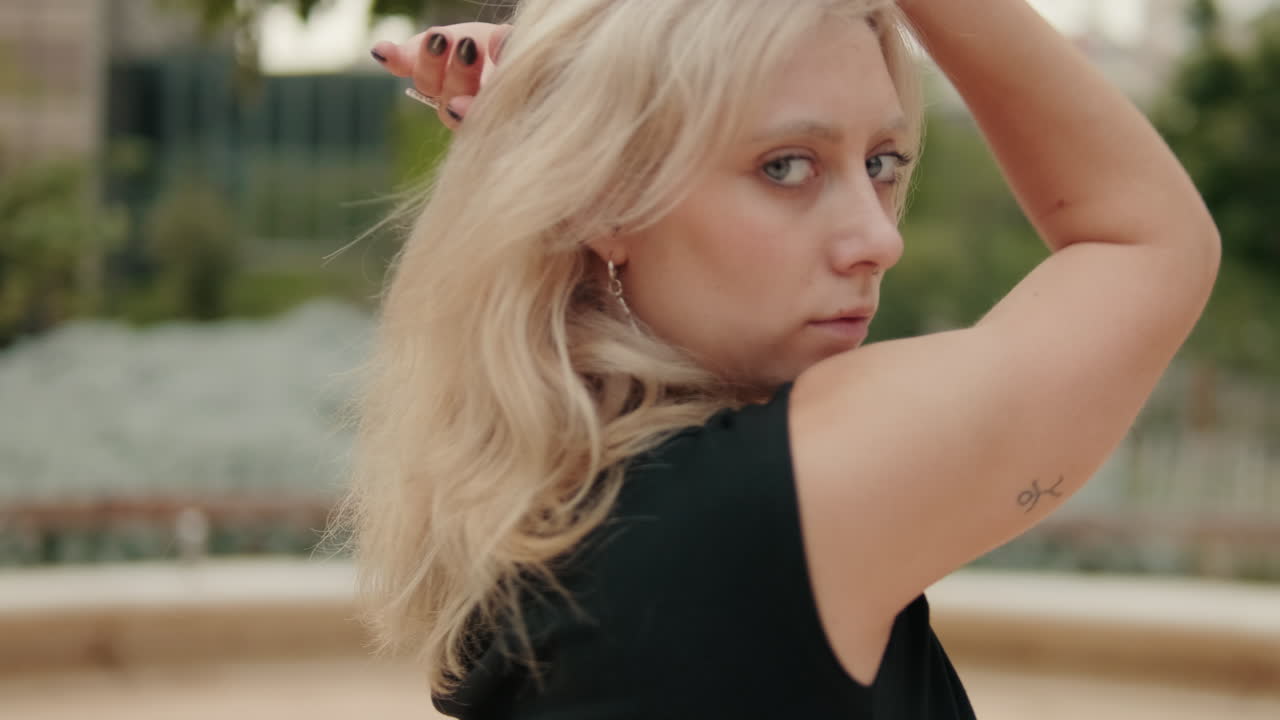 Jovem mulher loira realizando dança expressiva ao ar livre.