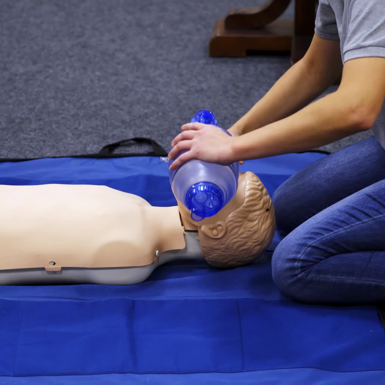 Training session for saving life. Instructor shows cardiac exercise on a mannequin. Demonstration of cpr on a dummy with breathing apparatus