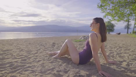 Side-slow-motion-view-of-attractive-girl-sitting-on-a-sandy-beach