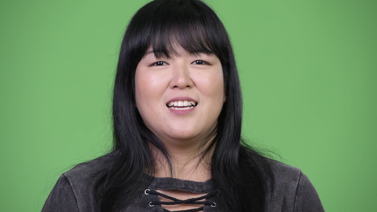 Beautiful overweight Asian woman talking to camera