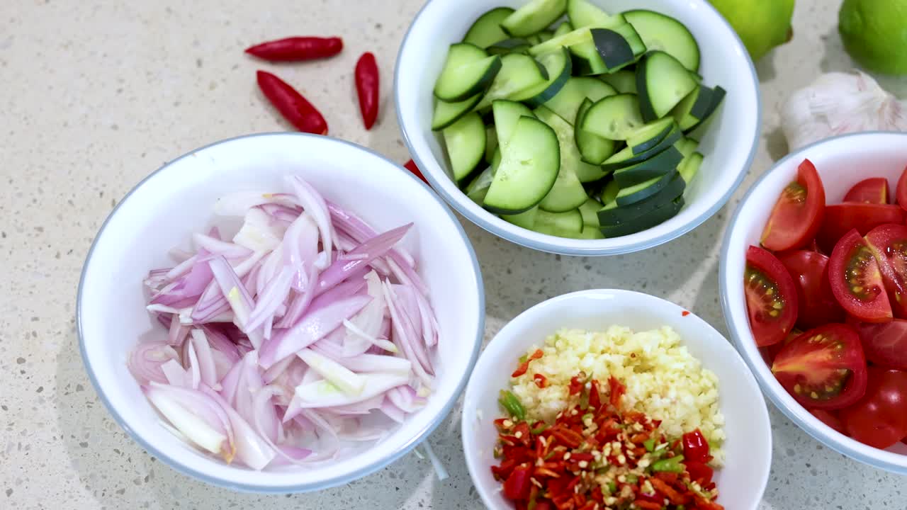 Top-down view of sliced vegetables in bowls on a kitchen counter, showcasing fresh ingredients under bright lighting