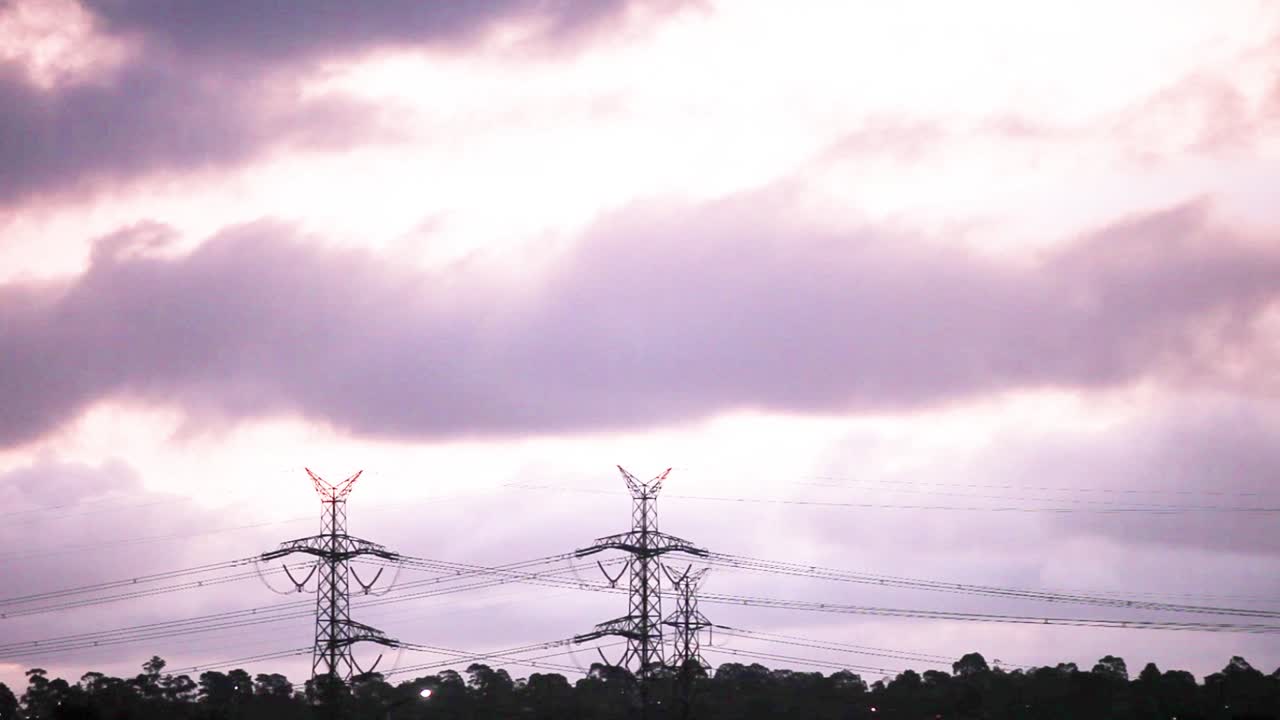 Storm clouds passing by electricity pylons in complete silhouette
