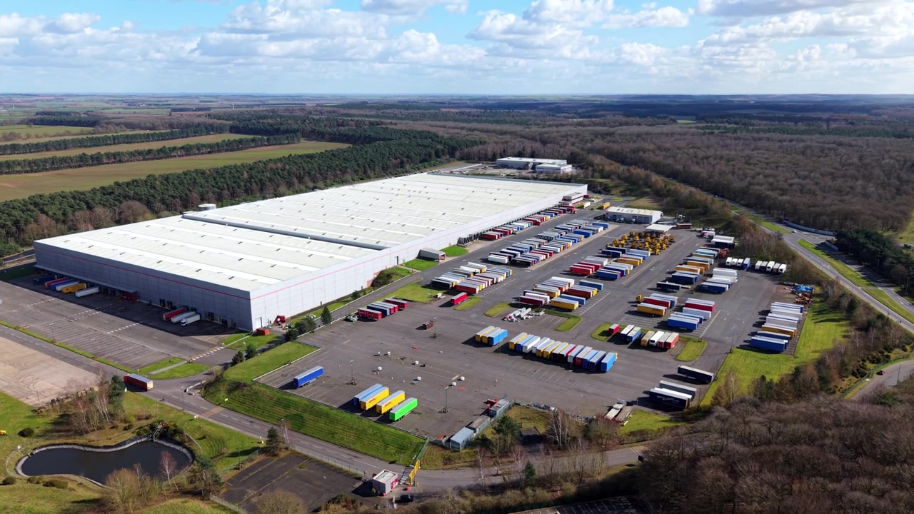 Expansive freight transport depot featuring complex terminal infrastructure, cargo loading platforms, and dense fleet parking arrays.