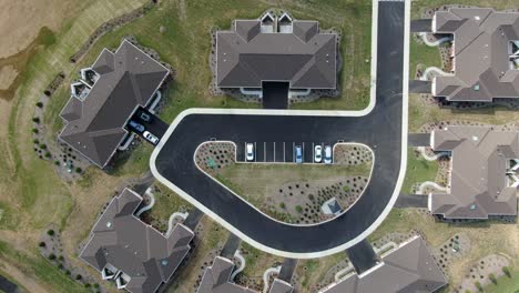 top down aerial birds eye overhead perspective, new home condo apartment construction, brown roof, new landscape and recently planted grass, cars parked in community retirement home, senior citizen