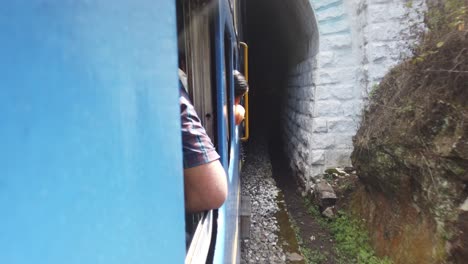 tourists look from the windows of the nilgiri mountain railway train as it enters a tunnel at ooty, udagamandalam, ootacamund, udhagai, tamil nadu, india.