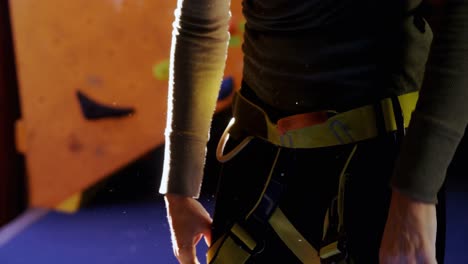woman wearing her harness at bouldering gym 4k