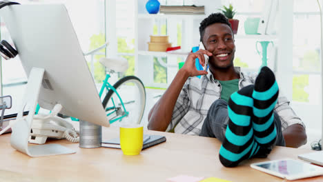 Male-executive-talking-on-mobile-phone-while-relaxing-at-his-desk-in-office-4k