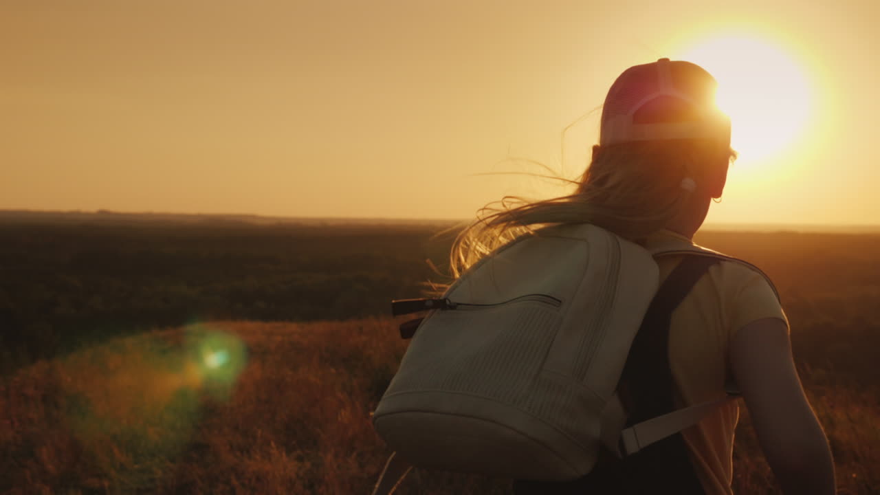 un niño despreocupado con una mochila detrás de él corre hacia el sol, las vacaciones de verano y el concepto de libertad