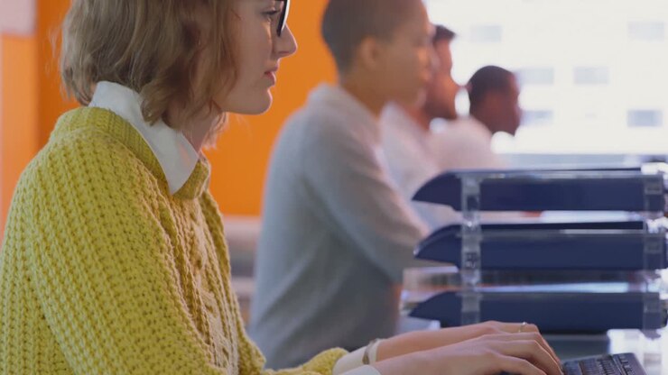 Vista laterale di giovani dirigenti caucasiche che lavorano alla scrivania in un ufficio moderno 4k