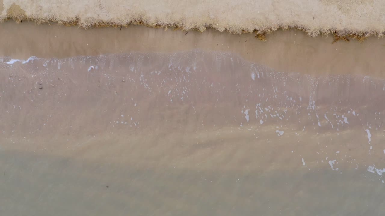 침식된 풍경에 대해 튀는 맑은 물과 함께 해변에서 부드럽게 부서지는 파도