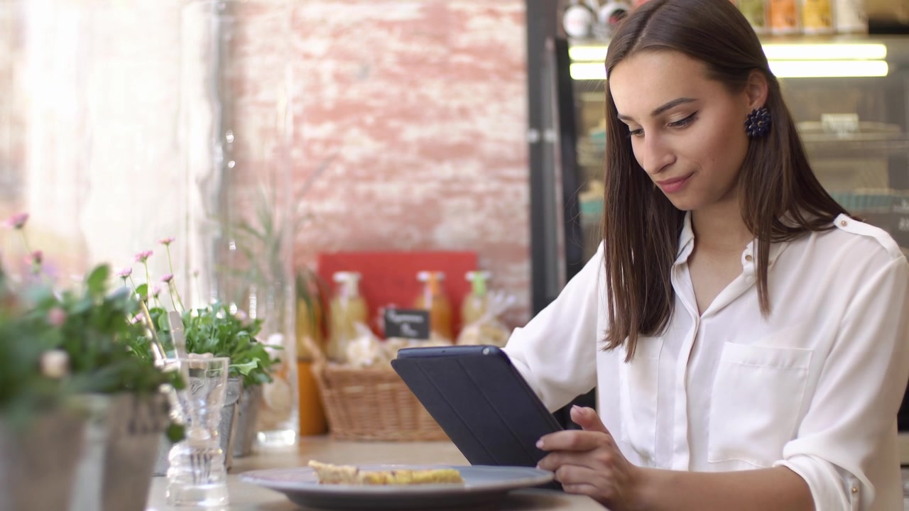 Fokuseret ung kvinde bruger tablet ved cafedisken