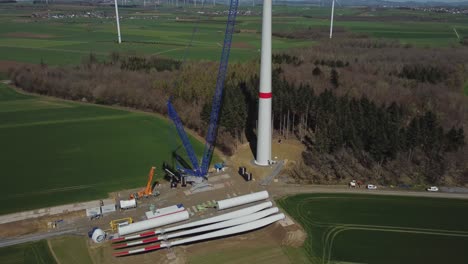 wind turbine during construction with different windmill parts on the ground - aerial drone shot