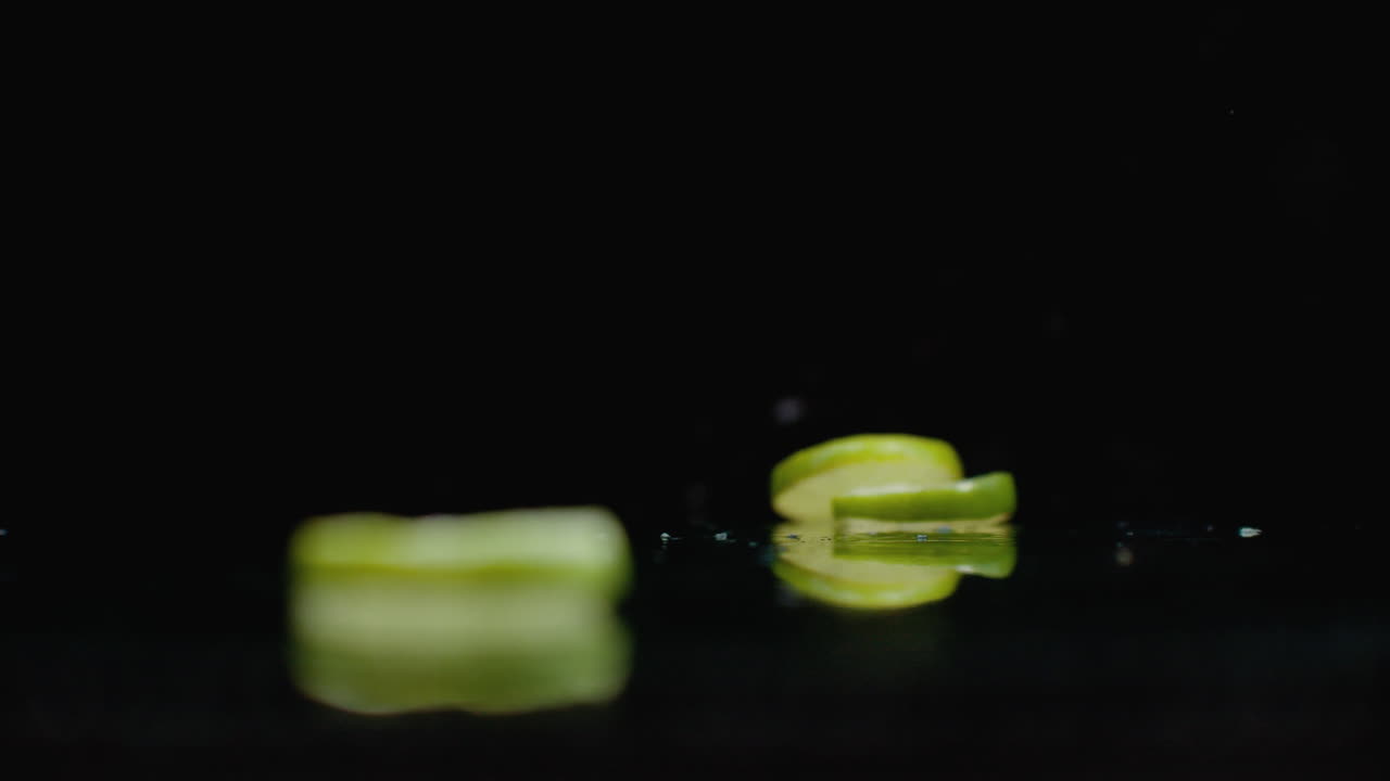 느린 동작: 개진 라임 링이 어두운 배경의 유리 위에 물 어리로 떨어집니다.