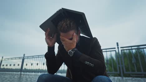 stressed man with laptop in the rain