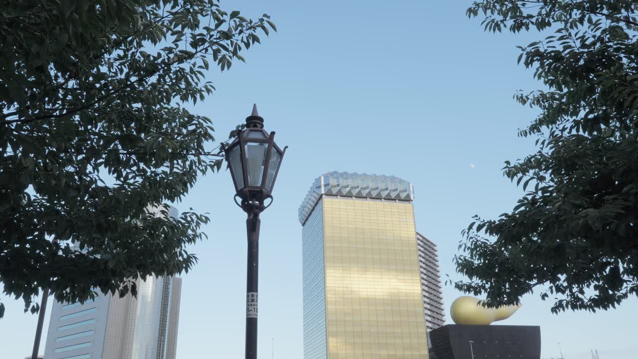 An antique-style streetlight in Sumida Park, with the iconic Asahi Beer Hall and modern Tokyo cityscape in the background