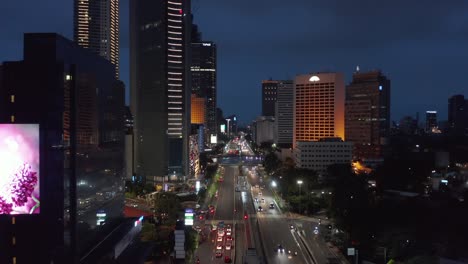 low flying aerial dolly shot of cars on a busy multi lane road in jakarta city center at night