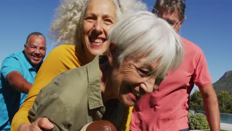 Happy-senior-diverse-people-playing-rugby-in-garden-at-retirement-home