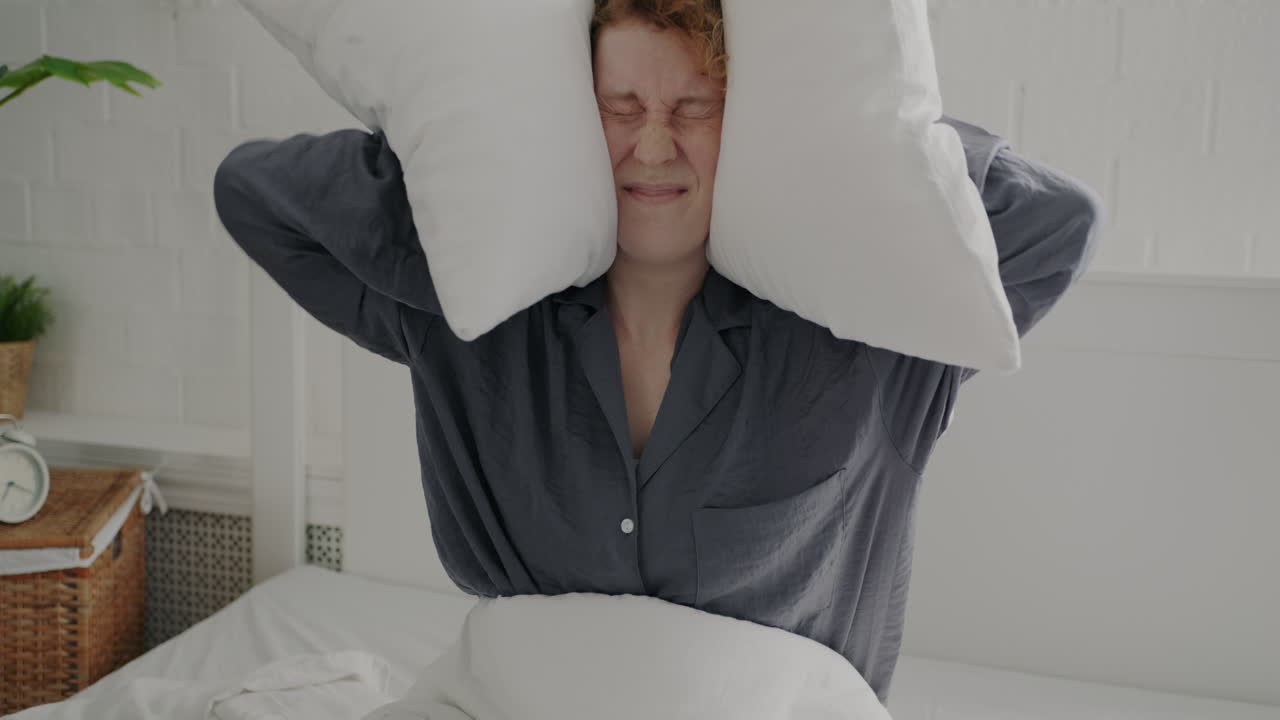 Woman having a playful pillow fight in bed