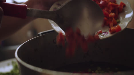 pouring sweet red pepper in pieces into a pot