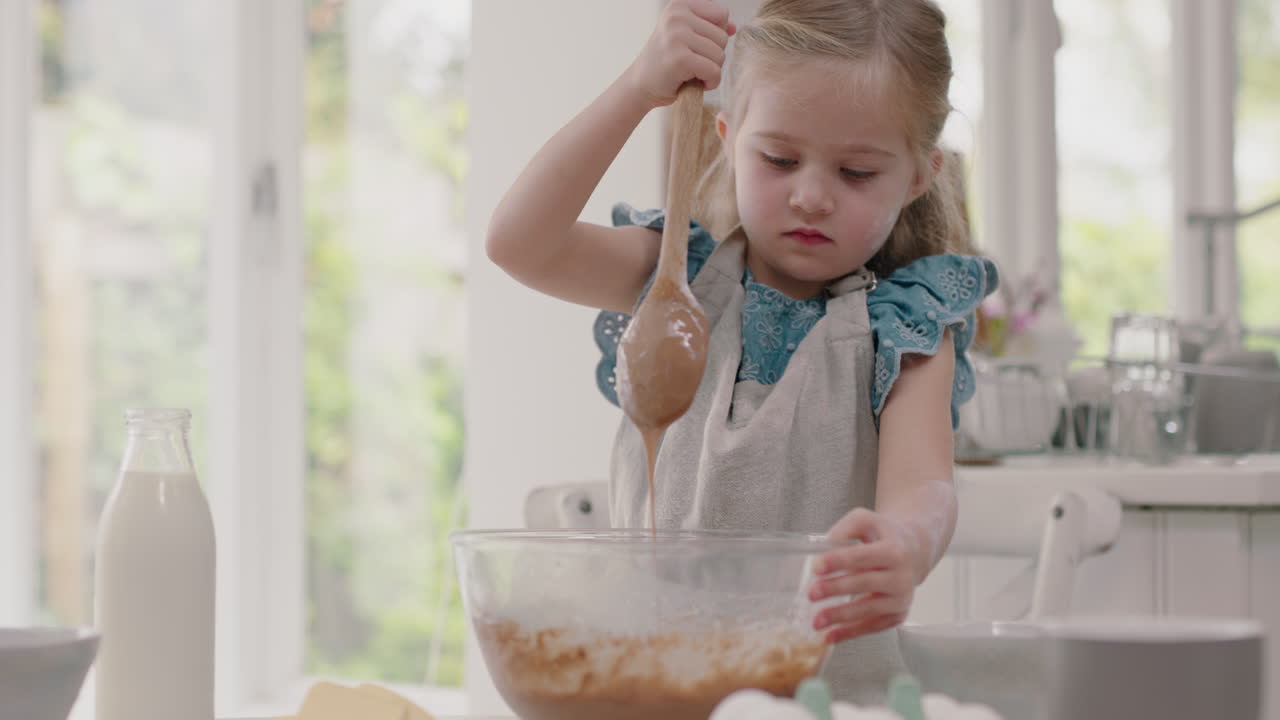 happy little girl baking in kitchen mixing ingredients for homemade cookie dough having fun preparing delicious treats for breakfast at home 4k footage