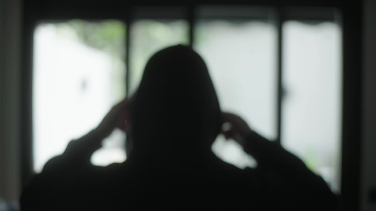 Person in Hoodie Looking Through Window