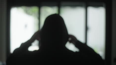 person in hoodie looking through window