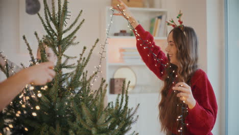 amigos jóvenes ajustando las luces en el árbol de navidad